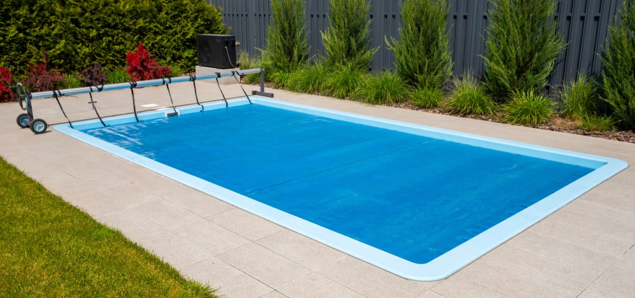 Swimming pool with protective cover to prevent autumn leaves and debris from entering water during fall season.