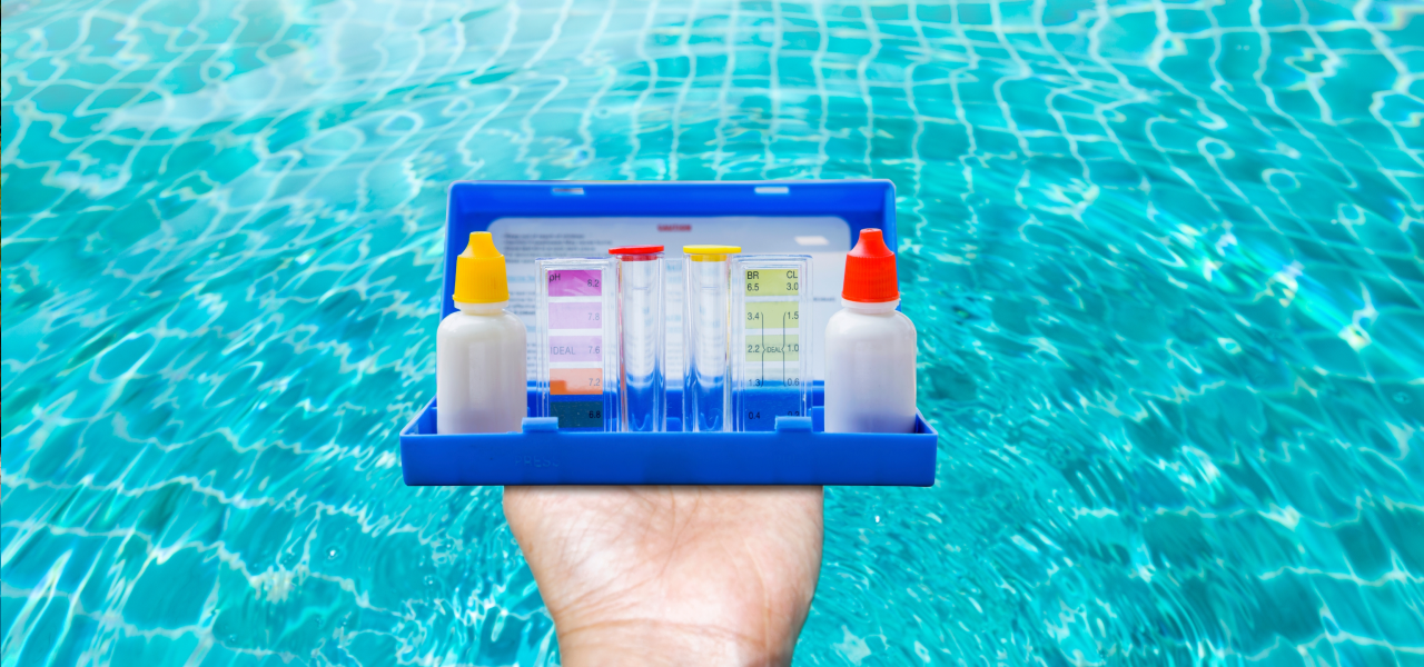 Hand holding pool water testing kit to check balance before closing pool when temperatures drop below 60 degrees.