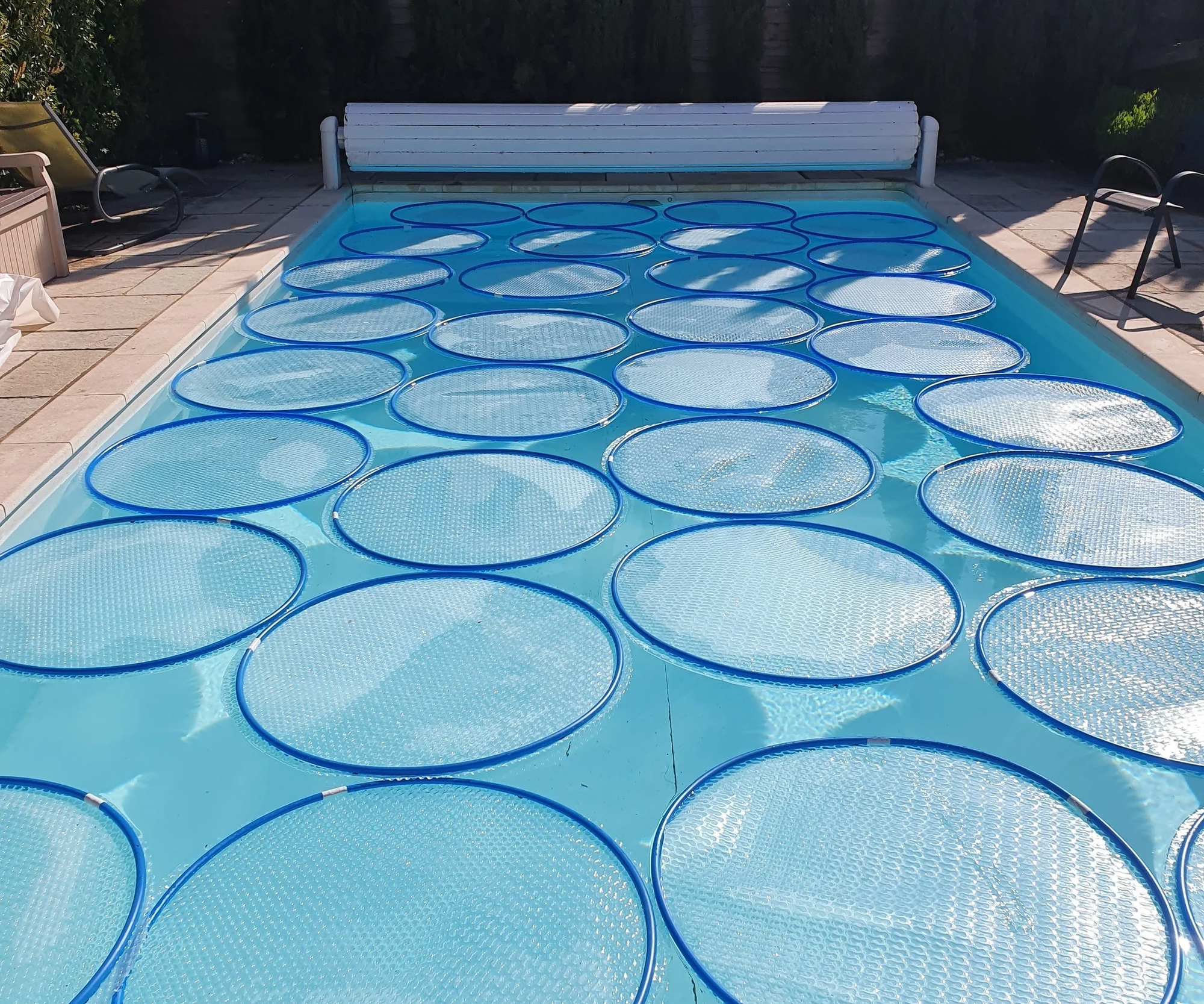 Solar rings floating on swimming pool surface to retain heat and reduce energy costs during cooler seasons.