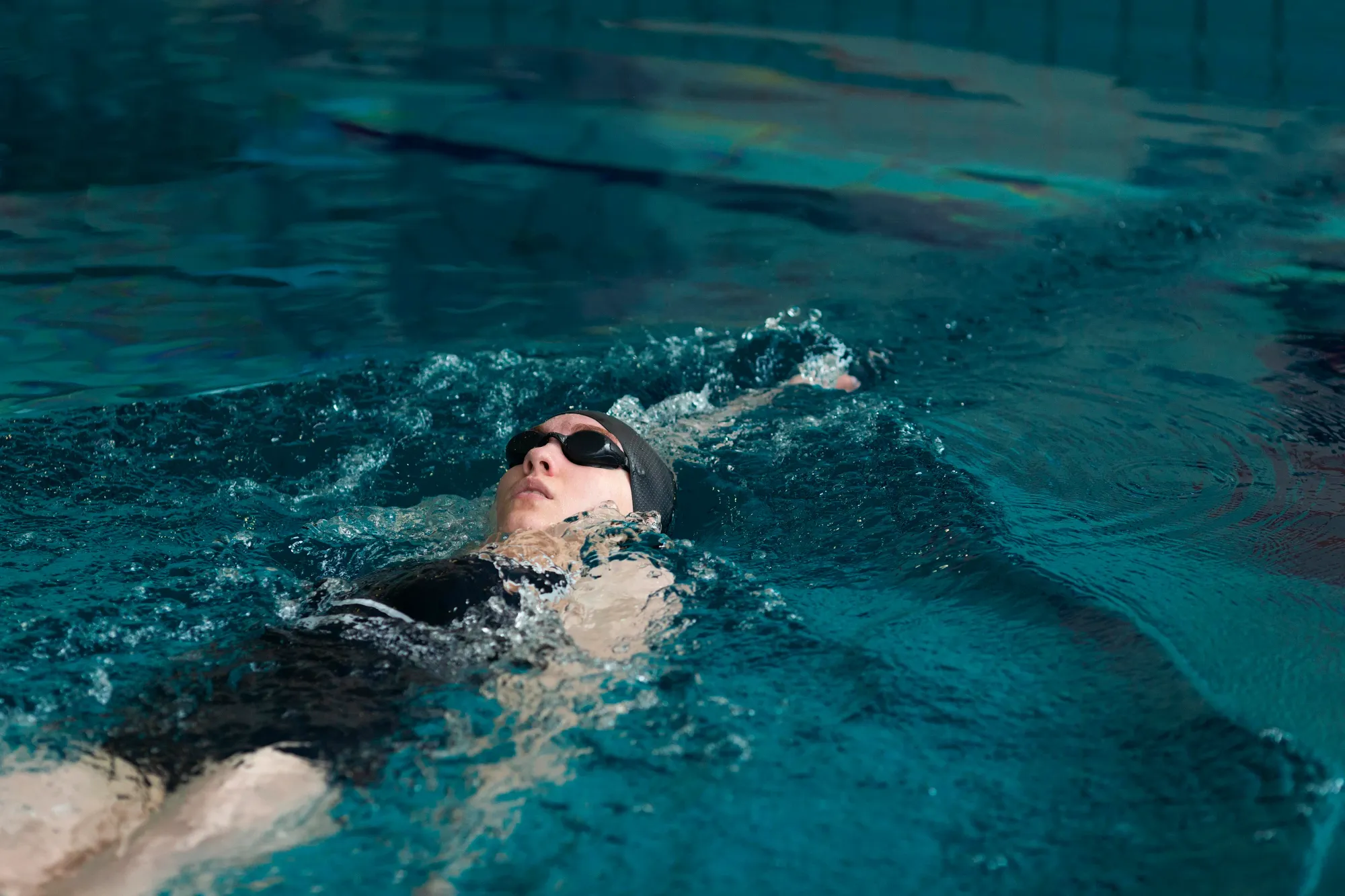 an athlete swimming the backstroke in an indoor pool