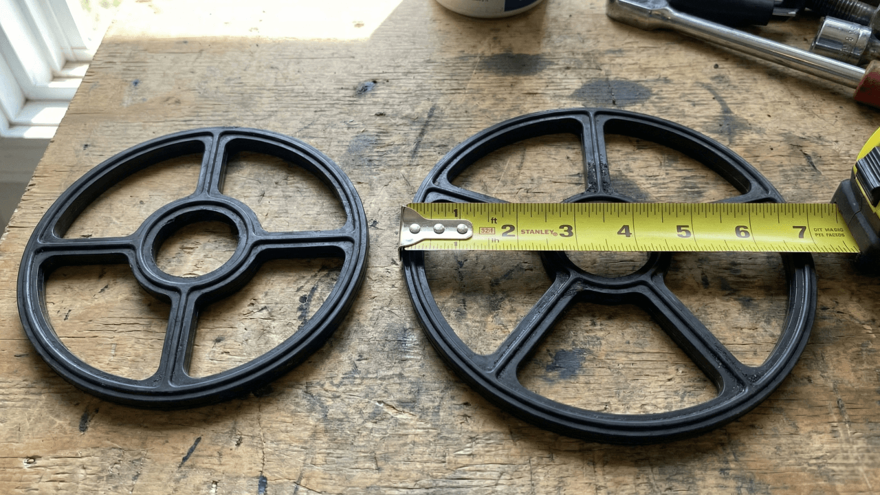 Two black spider gaskets side by side with tape measure showing outer diameter for sizing replacement in pool multiport valve.