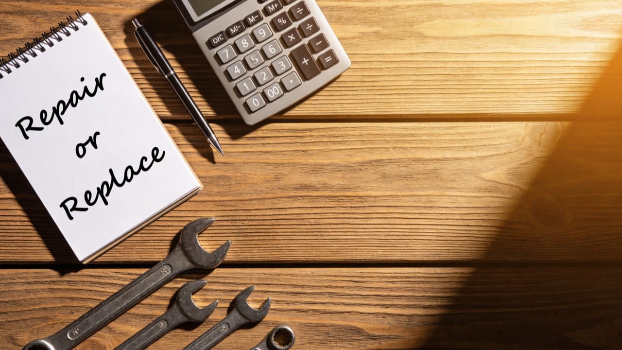 A calculator and notepad on a table helping a homeowner decide between repairing or replacing a pump.