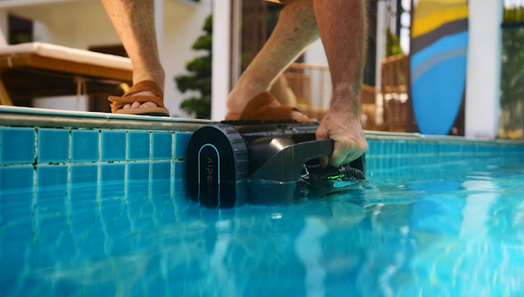 Robotic pool cleaner parked at the waterline for easy retrieval without bending or using a pole.