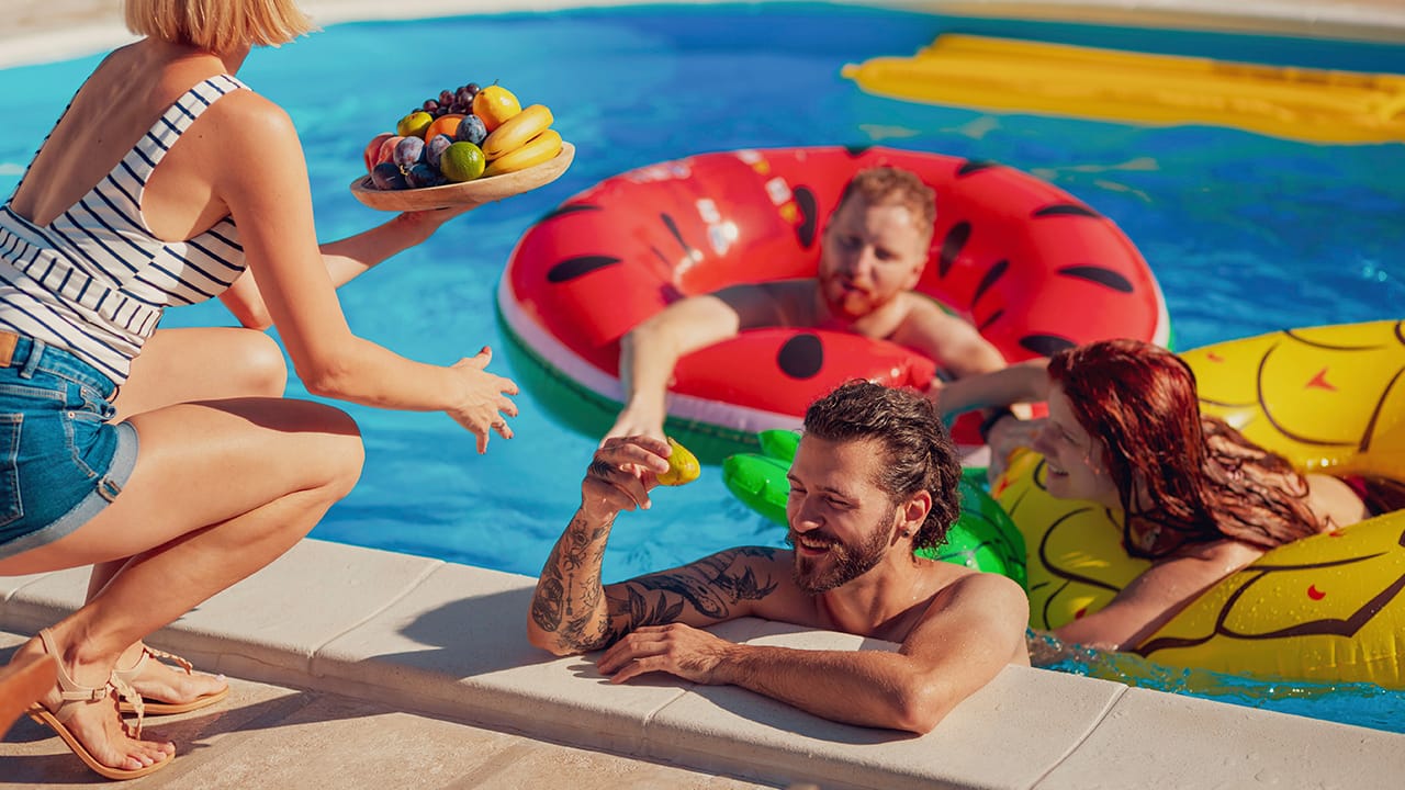 Friends enjoying a fun summer day in a clean, sparkling swimming pool, highlighting the importance of seasonal pool maintenance.