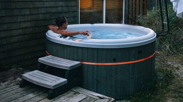 A man relaxing in a portable inflatable hot tub on a deck, illustrating the convenience and appeal of owning a budget-friendly spa.