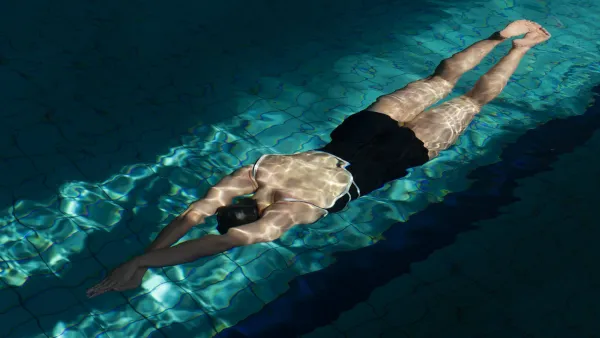 an athlete gliding underwater in a bright pool, highlighting the importance of a pre-swim barrier to prevent chlorine dryness.
