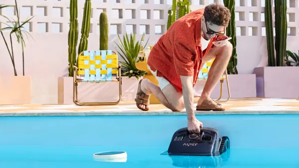 Homme mettant à l'eau un robot de piscine automatique pour démarrer le cycle de nettoyage.