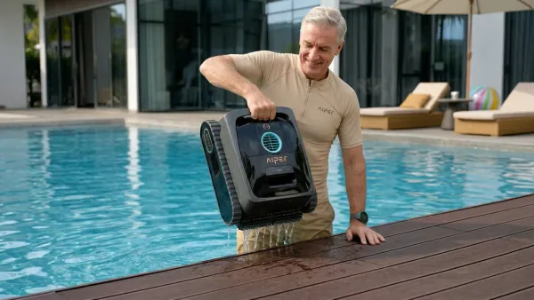 Senior adult easily lifting a lightweight cordless pool robot from the water with one hand on a clear deck.